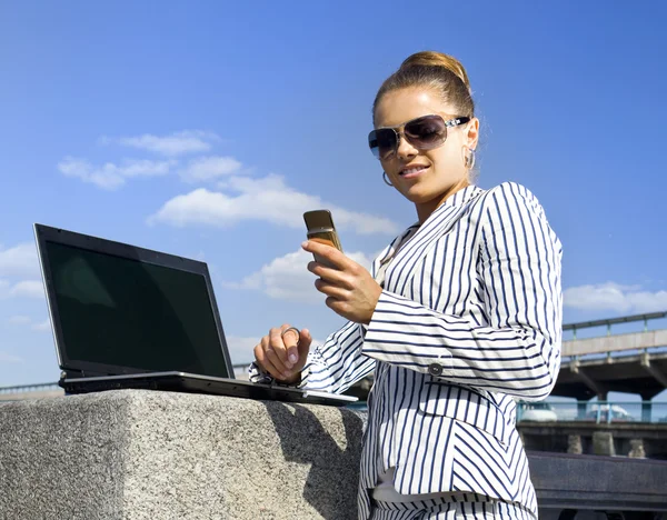 Kvinna med mobiltelefon och bärbar dator — Stockfoto
