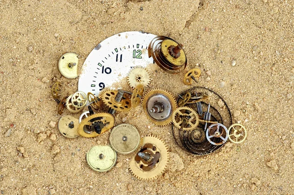 Pièces de mécanisme horloger sur le sable — Photo