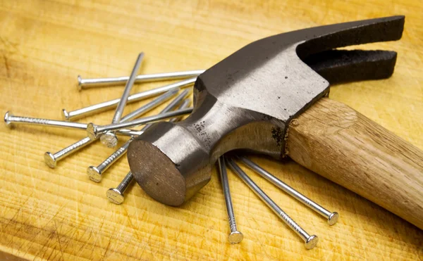Hammer und Nägel auf Holzbrett — Stockfoto