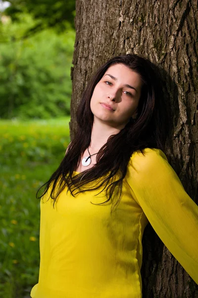 Beautiful woman standing by the tree — Stock Photo, Image