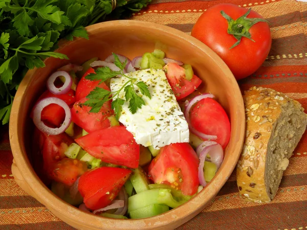 Griekse salade op een gestreepte tafellaken — Stockfoto