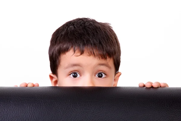 Criança Olhando Para Câmera Escondida Atrás Sofá Preto — Fotografia de Stock