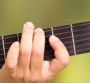 Hand playing guitar over green natural background clipart