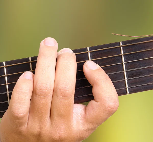 緑の自然な背景の上でギターを弾く手 — ストック写真