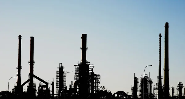 Petrol rafineri bacaları ile silüeti — Stok fotoğraf