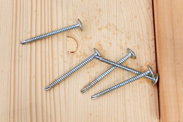 Five steel screws on a wooden plank — Stock Photo, Image