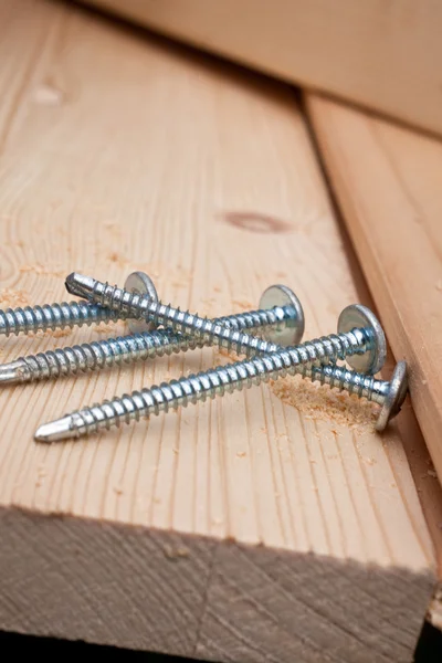 Four steel screws on a wooden plank — Stock Photo, Image