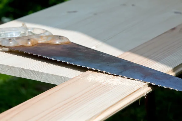 Old saw lying on wood planks — Stock Photo, Image