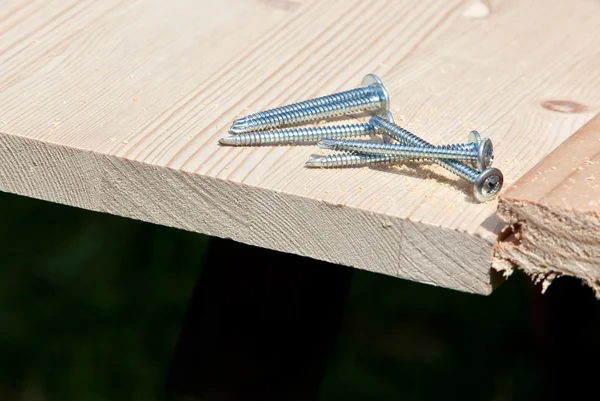 Six steel screws on wood plank — Stock Photo, Image