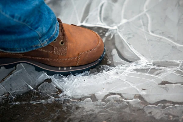 Мужская нога в ботинке раздавливает тонкий лед — стоковое фото