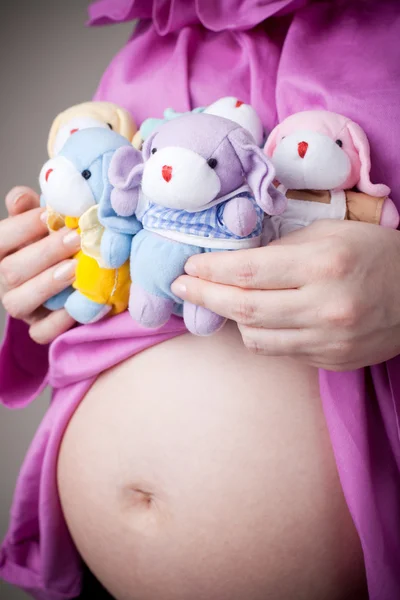 坐在怀孕的肚子上的玩具熊 — 图库照片