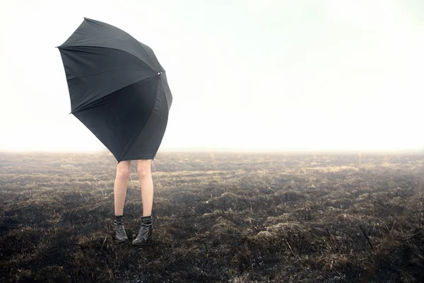 Girl with umbrella on black field — Stock Photo, Image