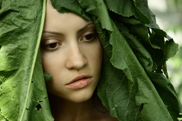 Schönes Mädchen mit großen Blättern auf dem Kopf — Stockfoto