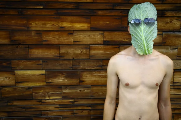 Молодой человек в маске из листьев капусты — стоковое фото