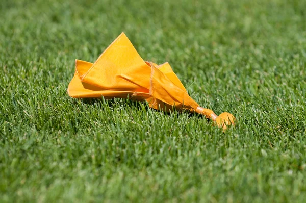 Желтый штрафной флаг на зеленой траве — стоковое фото