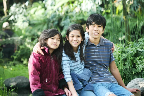 Drie kinderen zitten buiten — Stockfoto