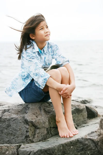 Nine year old girl sitting by lake — Stock Photo, Image