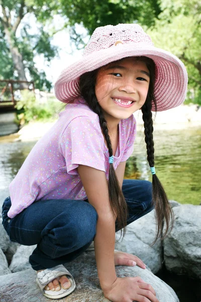 Little girl playing on rocks by river — Stock Photo, Image