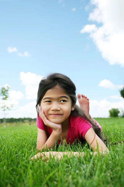 Klein meisje liggend op gras in de zomer — Stockfoto