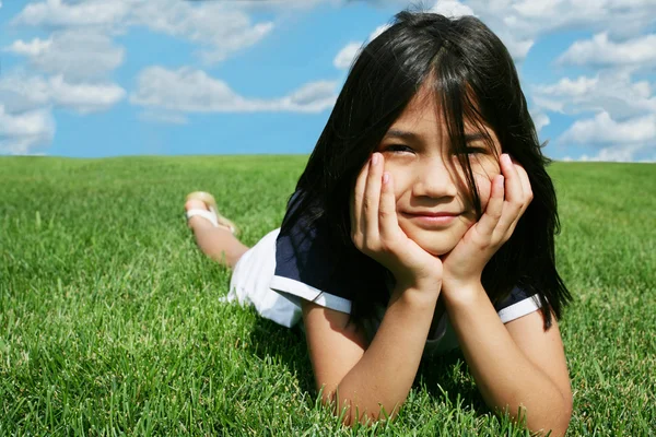 Kleines Mädchen liegt im Sommer im Gras — Stockfoto