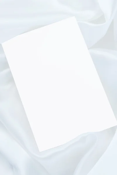 Tarjeta blanca en blanco sobre satén blanco — Foto de Stock