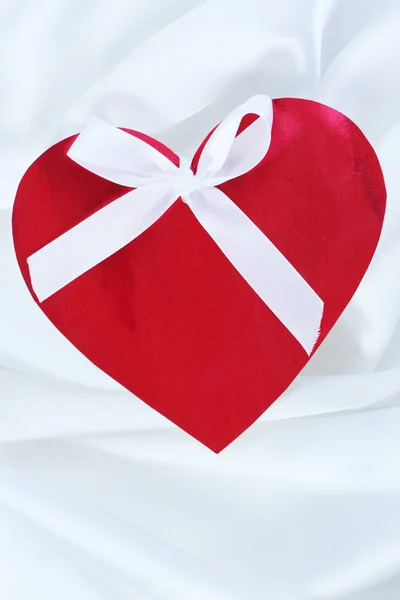 Red heart with ribbon on white satin — Stock Photo, Image