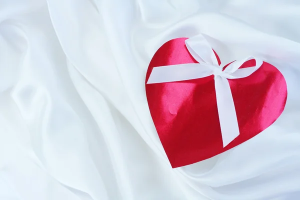 Red heart with ribbon on white satin — Stock Photo, Image