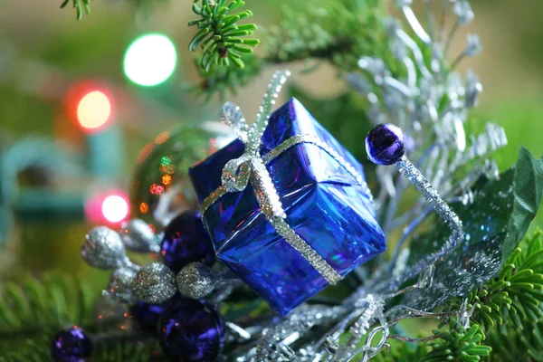 Μπλε παρόν στολίδι φωλιασμένο σε χριστουγεννιάτικο δέντρο. — Φωτογραφία Αρχείου