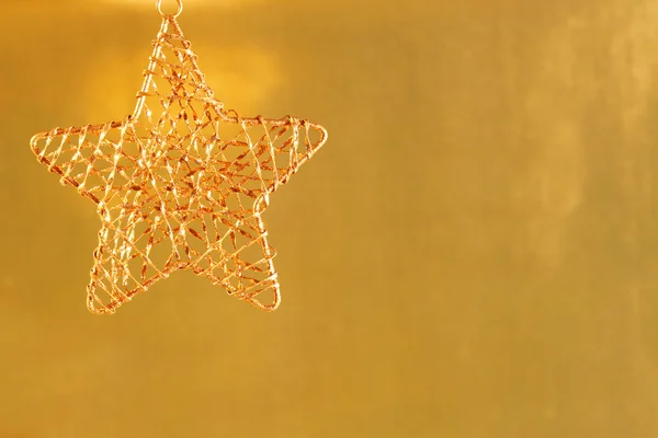 Gold star ornament on gold shiny background.