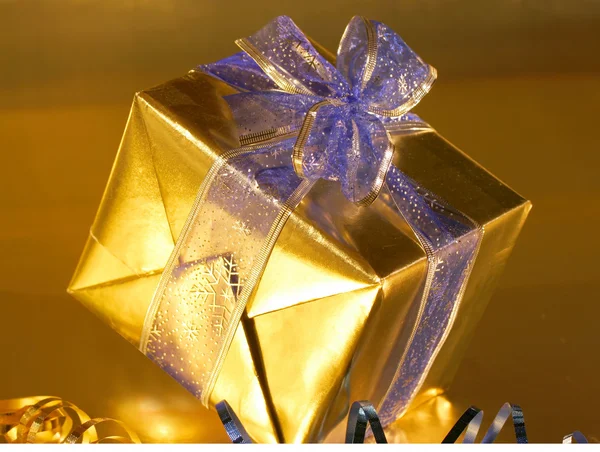 Elegant gold present with blue ribbons on gold — Stock Photo, Image