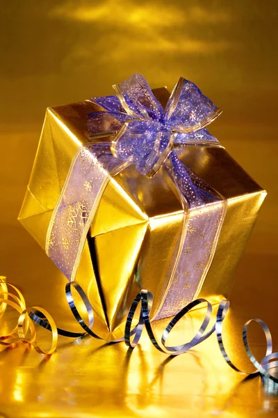 Elegant gold present with blue ribbons on gold — Stock Photo, Image