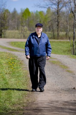 Elderly man walking on country road clipart