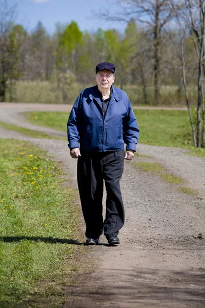 Uomo anziano che cammina sulla strada di campagna — Foto Stock