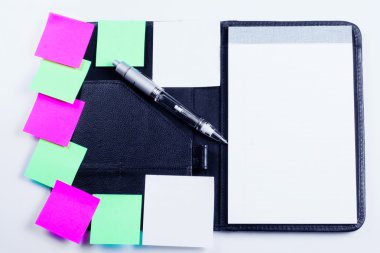 Black planner with sticky notes and pen clipart