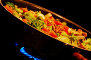 Chicken and vegetable stirfry in a wok; clipart