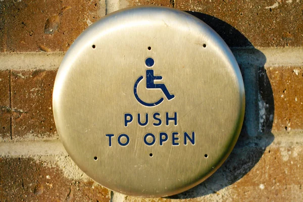 Handicap nabízenou otevřít tlačítko podél vnější cihlová zeď — Stock fotografie