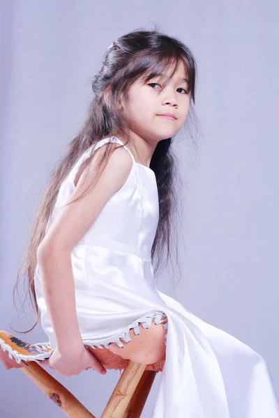 Красивая маленькая девочка в белом атласном платье — стоковое фото