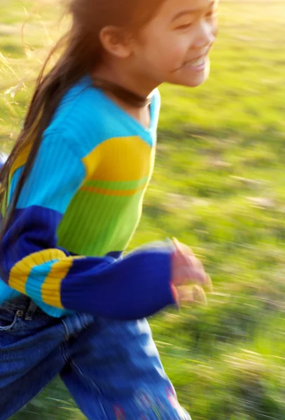 Small girl running happily through green field — Stock Photo, Image