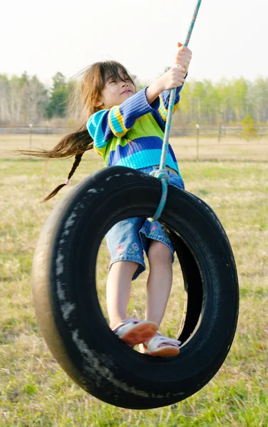 Holčička na pneumatiky swing — Stock fotografie
