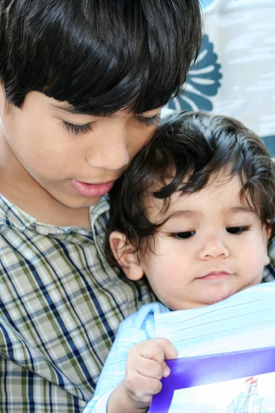 Big brother reading to baby brother — Stock Photo, Image