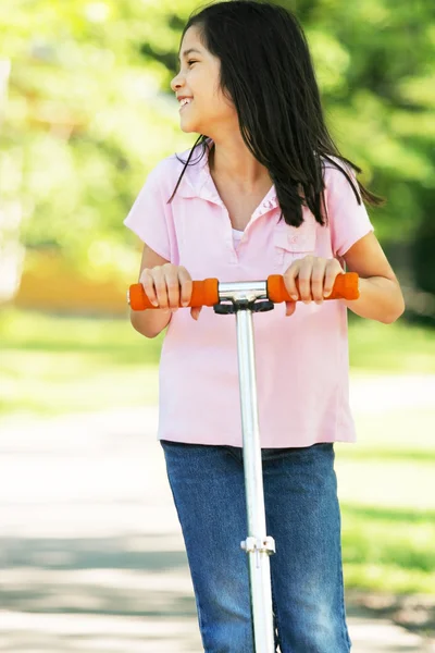 Girl riding a scooter on sidewalk — Stock Photo, Image
