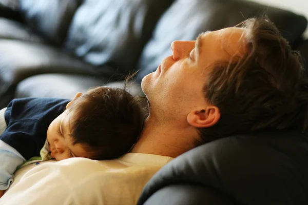 Малыш спит на груди своего отца .; — стоковое фото