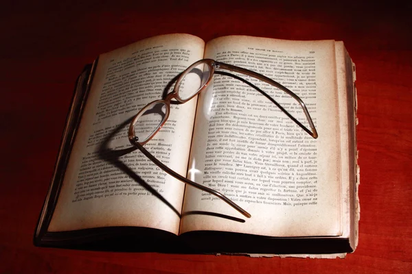 Старая книга и очки на столе . — стоковое фото