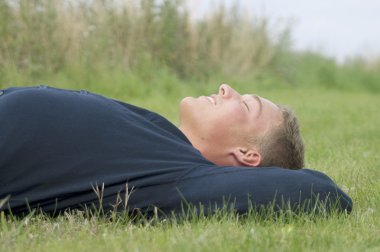 Young man lying in the grass clipart