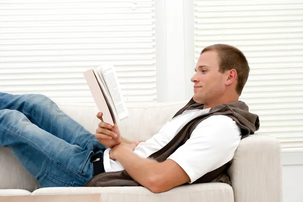 Çekici bir adam kitap okumak gülüyor — Stok fotoğraf