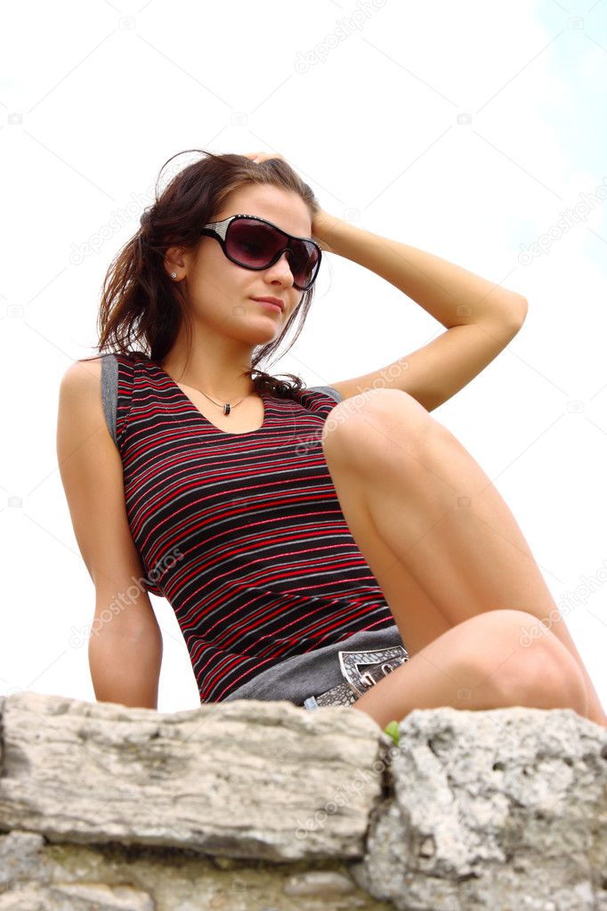 Fashion brunette woman sitting on a rock