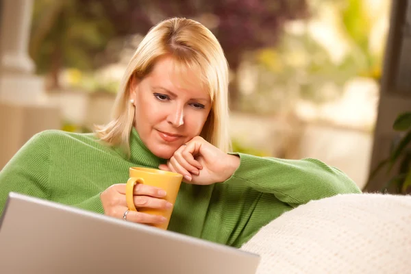 Lächelnde Frau mit Tasse mit Laptop — Stockfoto
