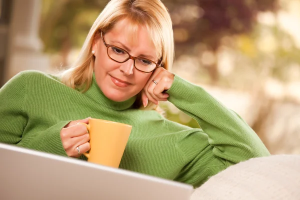 Усміхається жінка з чашки, використовуючи ноутбук — стокове фото