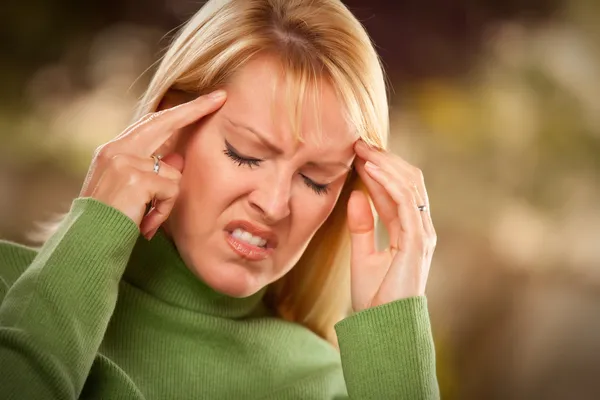 Grijnzende vrouw lijden een hoofdpijn — Stockfoto