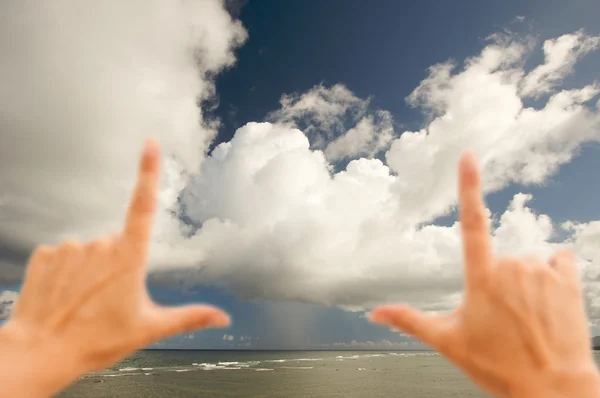 Mains encadrant des nuages de plage dramatiques — Photo